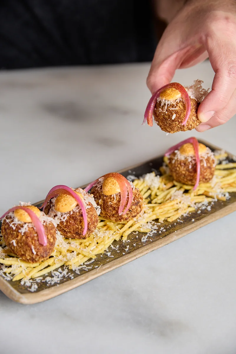 Croquetas caseras con cebolla encurtida sobre patata paja, Hatillo